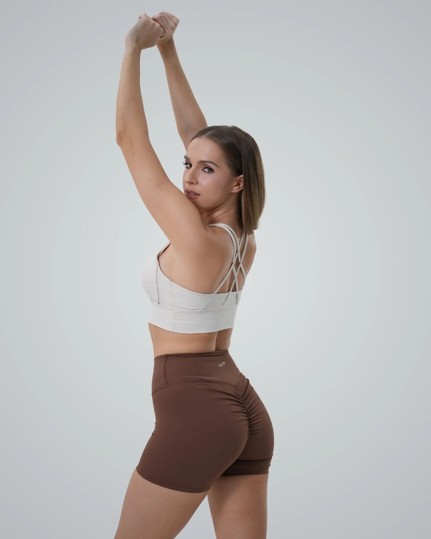 Model wearing Bandsam Edge Pro Set, featuring a white sports bra and brown shorts, ideal for seamless gym set or athleisure co-ord style.