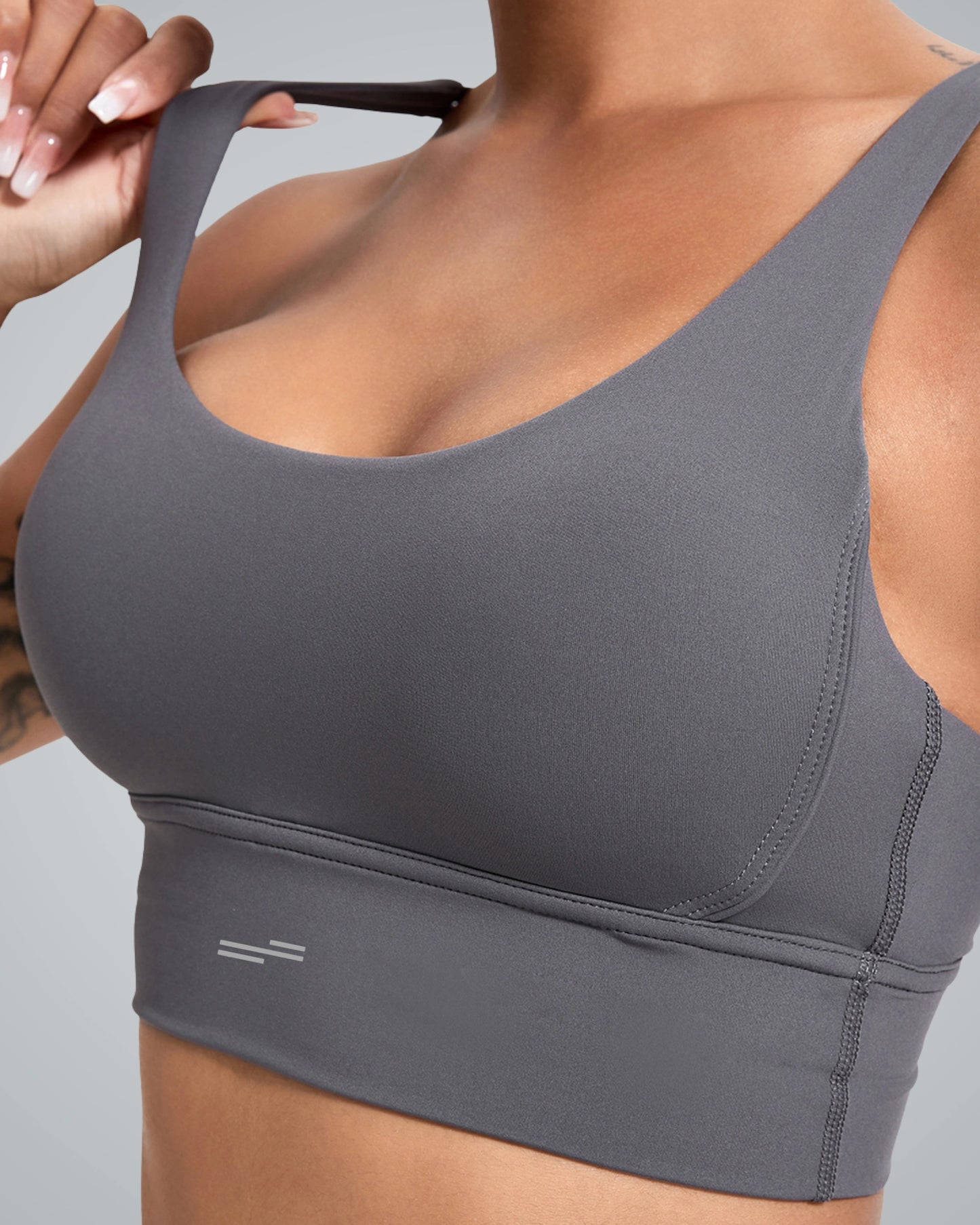 Close-up of a woman wearing a Bandsam sleek gray sports bra with a wide band and adjustable straps. The fabric appears smooth and stretchable, suited for activewear.