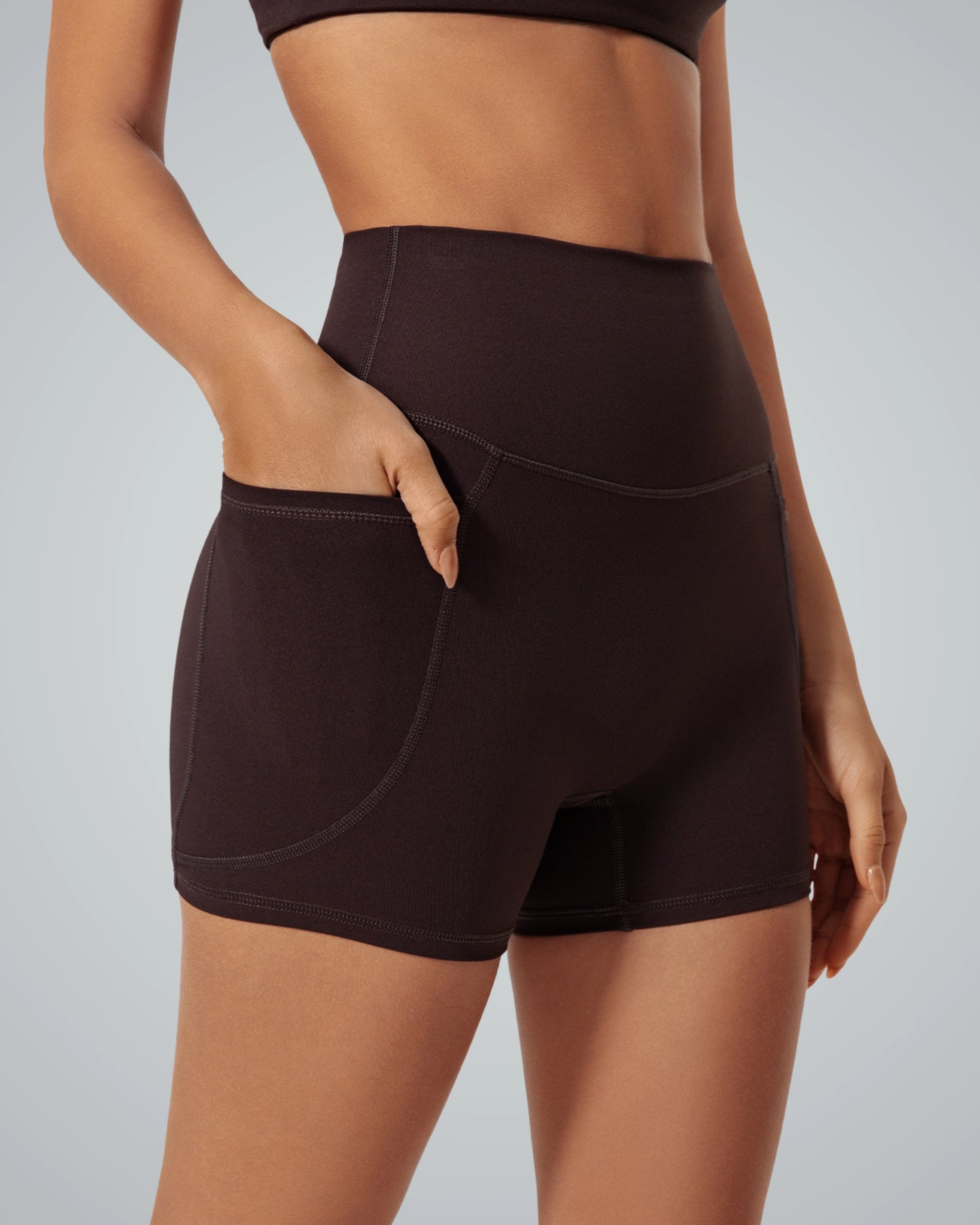 Woman wearing high-rise Bandsam LilaFit Shorts, ideal for yoga, pilates, and lounging. Features stretch, support, and a handy pocket.