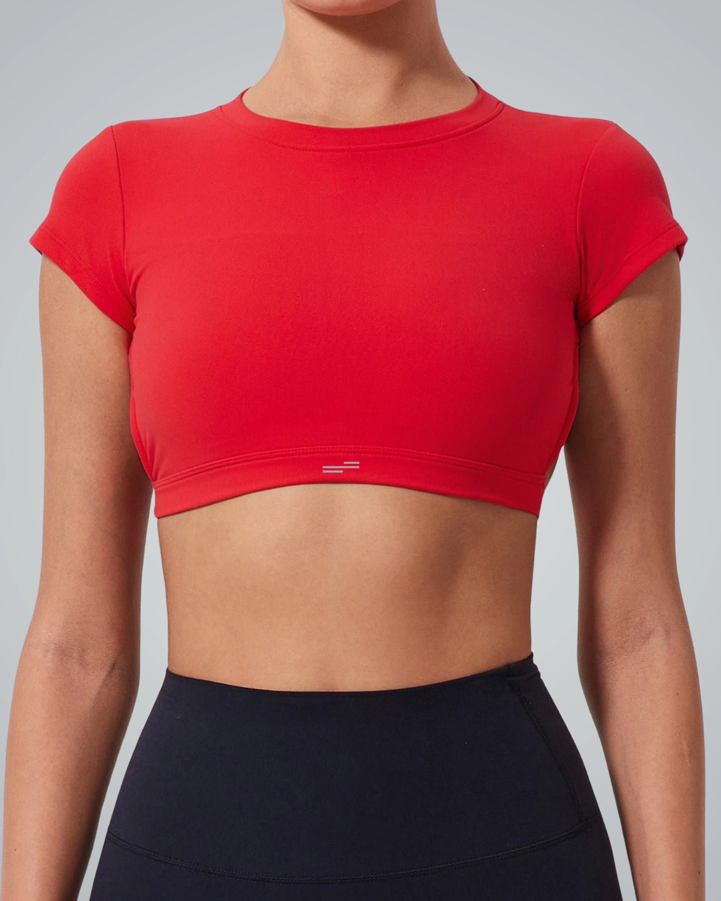 A person wearing a Bandsam fitted short-sleeve red crop top and high-waisted black leggings—perfect staples for an exercise wardrobe—is shown from the shoulders to the hips against a plain background.