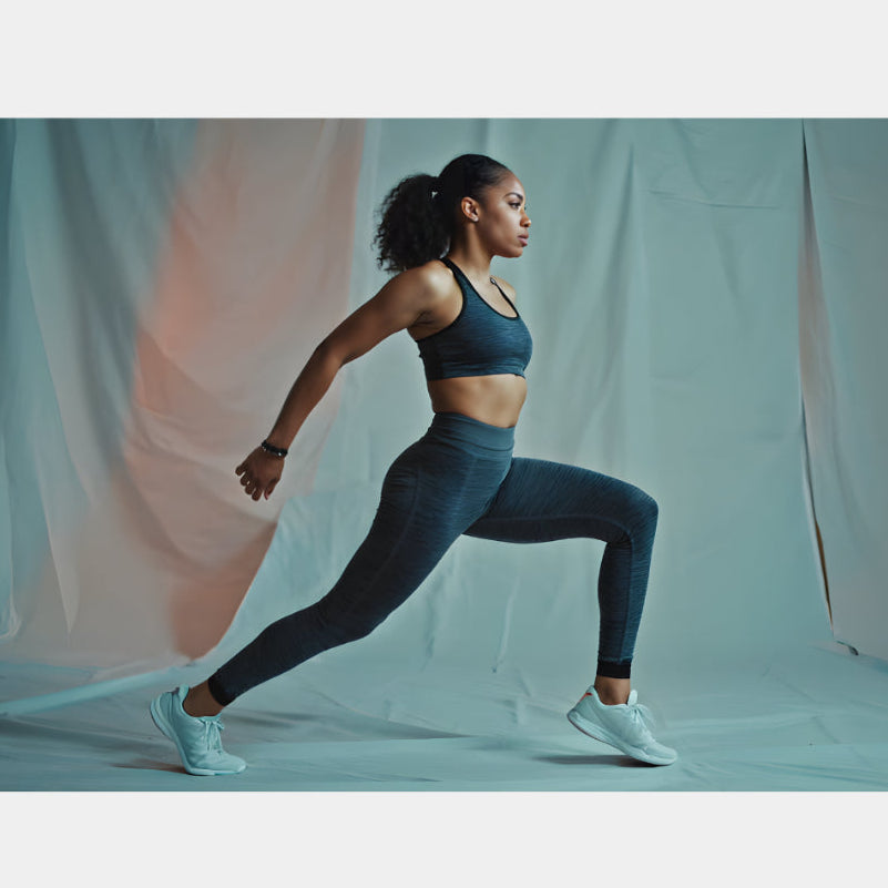 Woman in athletic wear performing a lunge against a plain background