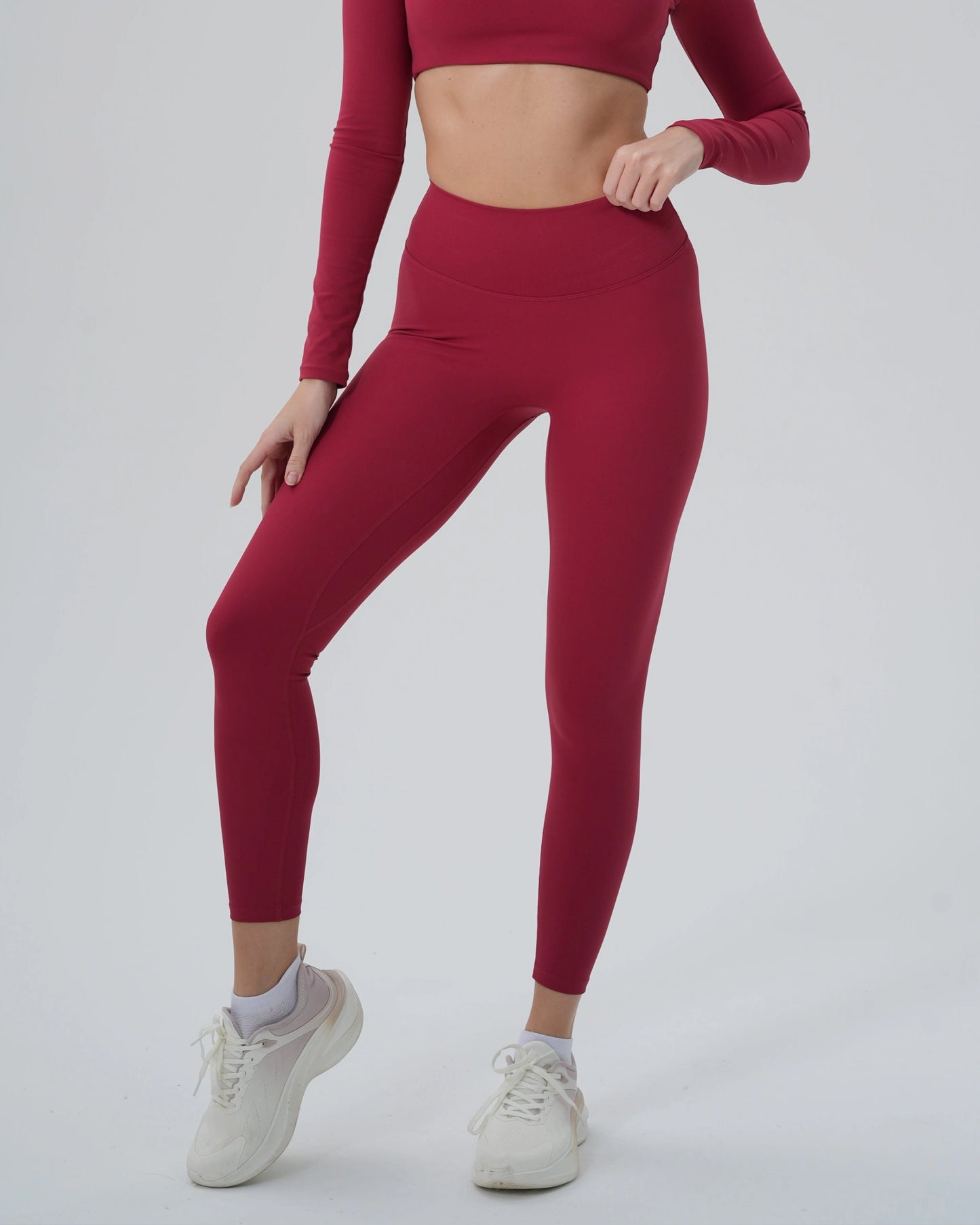 Woman wearing red Bandsam AllureFit Leggings for yoga, offering stretch, comfort, and support for workout or lounging activities.