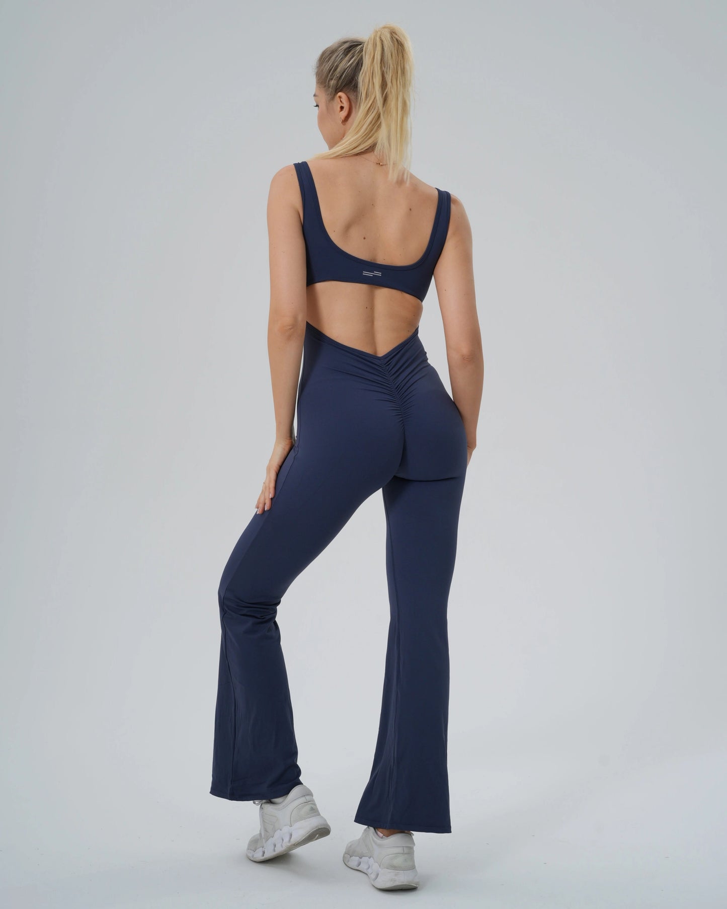Woman wearing Bandsam AuraFlow Jumpsuit, featuring flared legs and back cutout, ideal for yoga, pilates, and lounging.
