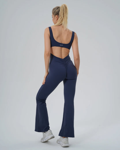 Woman wearing Bandsam AuraFlow Jumpsuit, featuring flared legs and back cutout, ideal for yoga, pilates, and lounging.