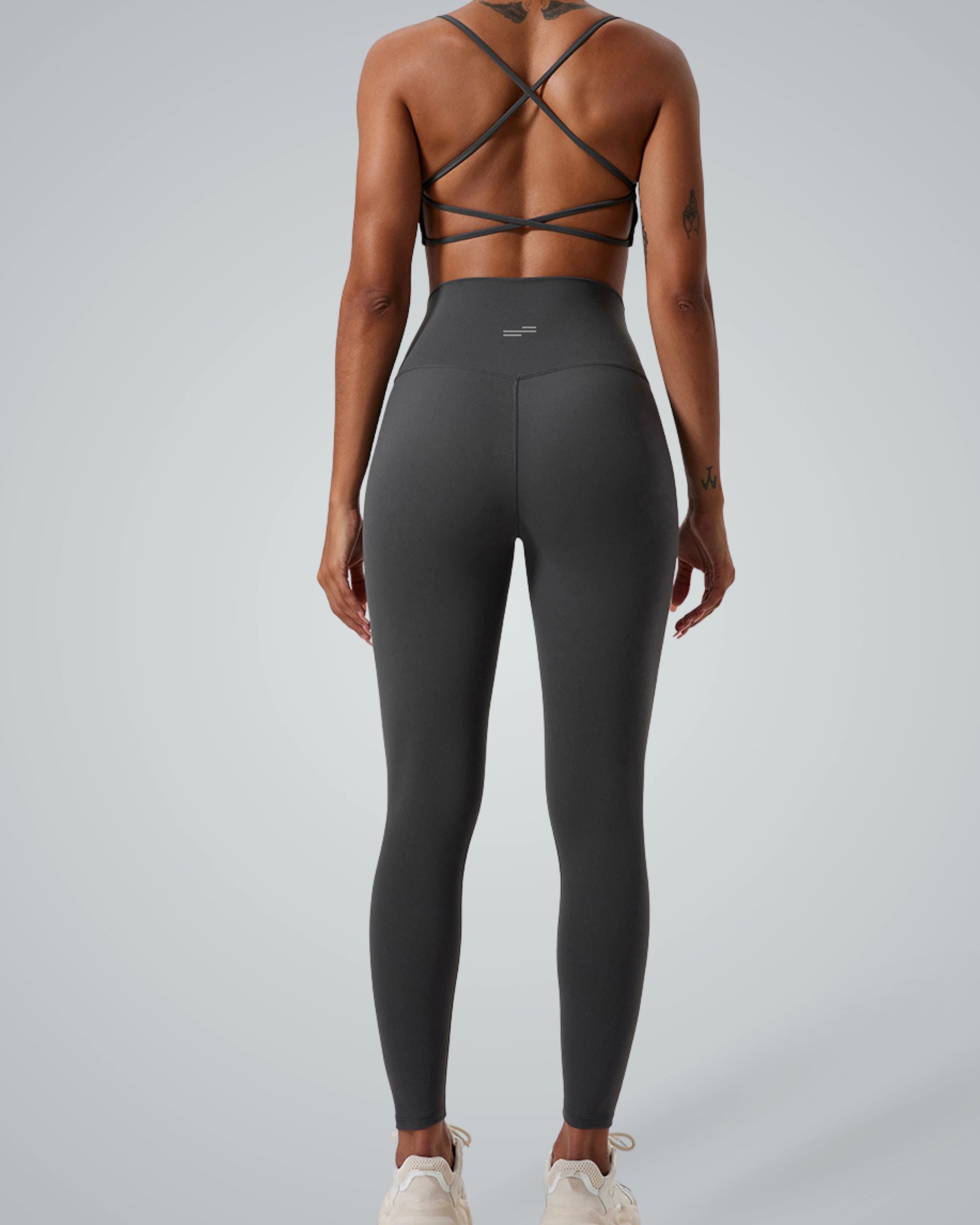 Back view of woman in Bandsam ContourCore Matching Workout Set featuring high-waisted leggings and strappy sports bra in sleek grey.