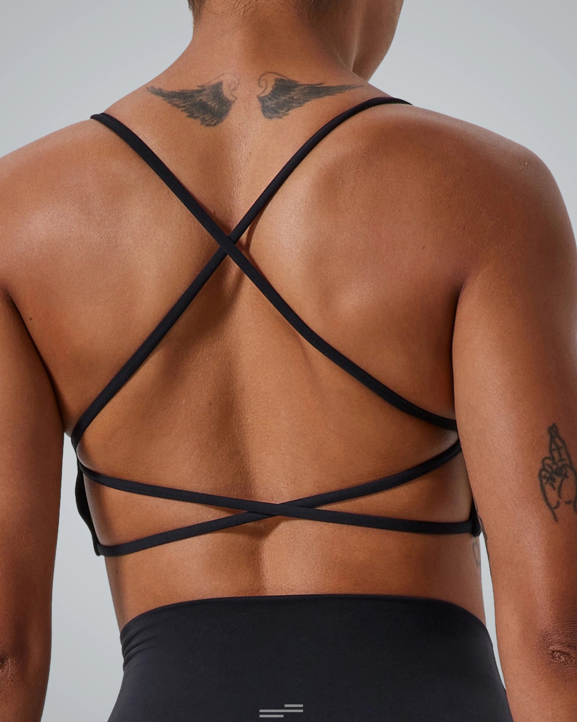 Back view of a woman wearing Bandsam Cross Flow Bra, showcasing breathable fabric and crisscross straps. Stretch, activewear, yoga-ready.
