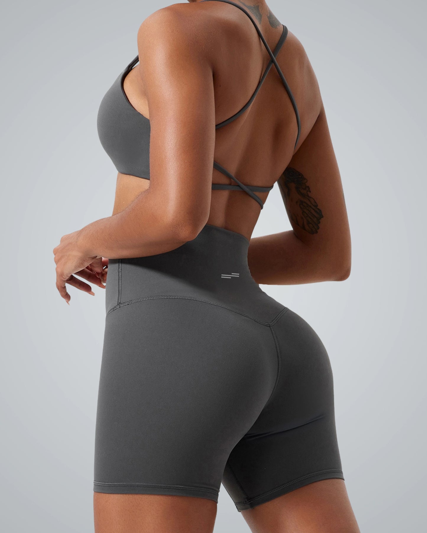 Woman wearing Bandsam Cross Flow Bra, gray activewear showing stretch and comfort, ideal for yoga and workouts.