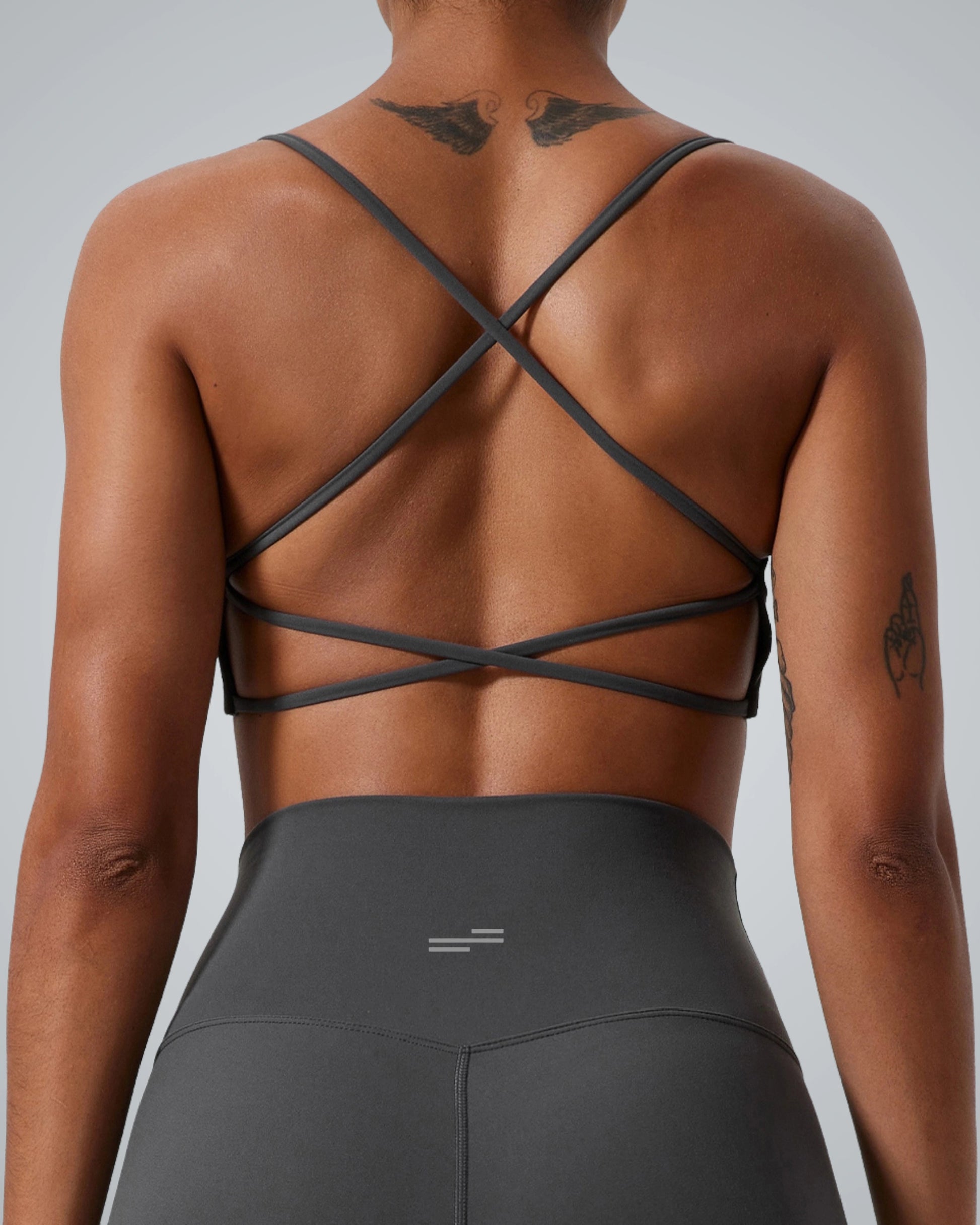 Back view of a woman wearing a Bandsam Stretch Cross Flow Bra, designed for yoga and workouts, featuring a strappy soft activewear design.