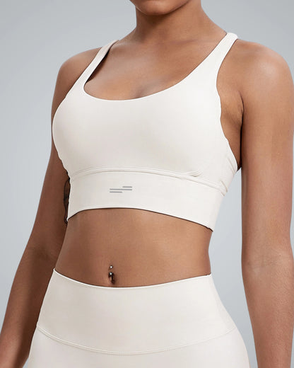 A woman wearing a Bandsam white, breathable workout bra and matching high-waisted leggings stands against a plain gray background. Only her torso and part of her arms are visible.