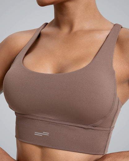 A close-up of a Bandsam fitness bra in a warm brown hue, featuring a simple design with wide straps and subtle stitching details. The model displays the bra's fit against a neutral gray background, highlighting its athletic style.