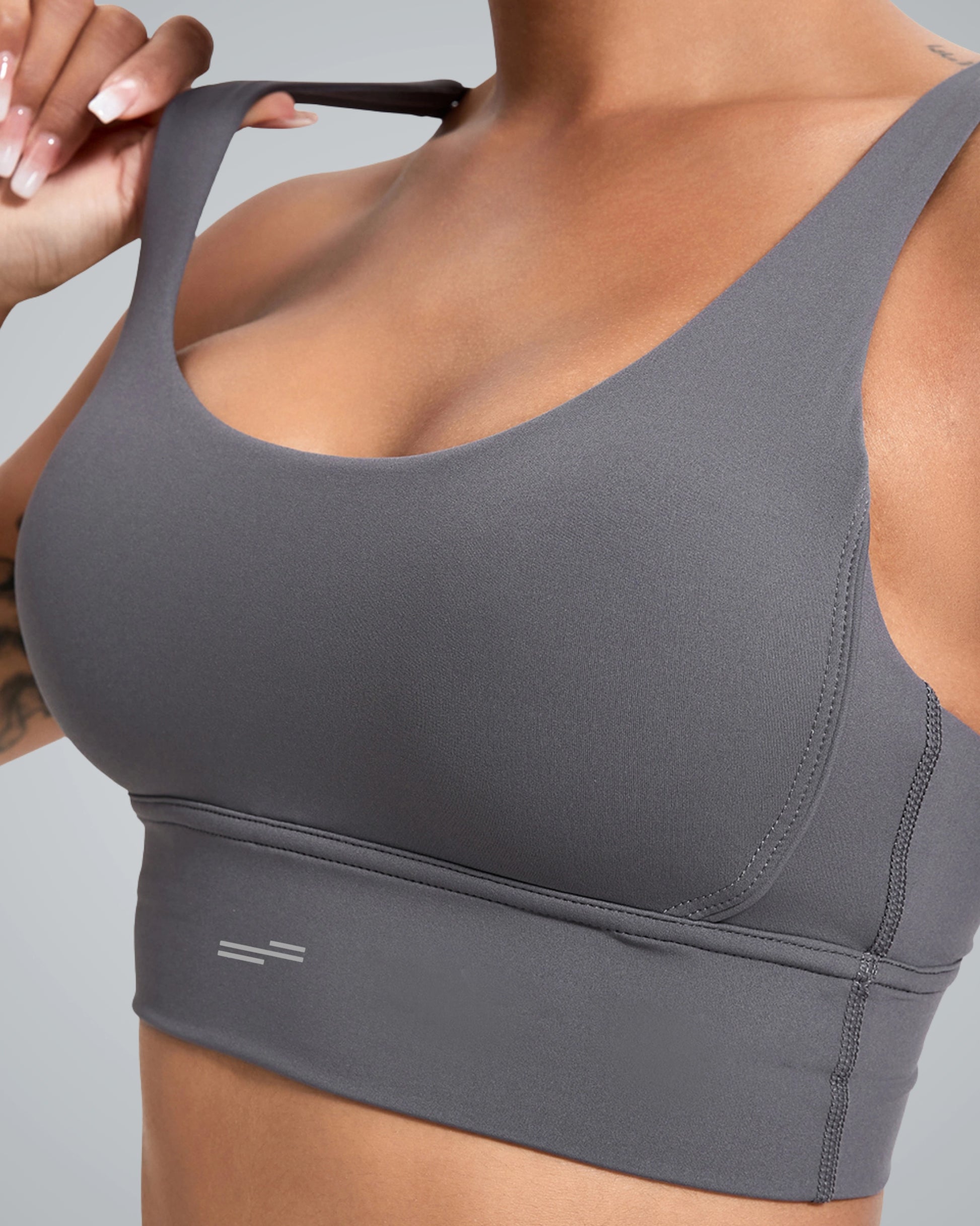 Close-up of a woman wearing a Bandsam sleek gray sports bra with a wide band and adjustable straps. The fabric appears smooth and stretchable, suited for activewear.