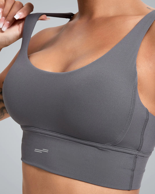 Close-up of a woman wearing a Bandsam sleek gray sports bra with a wide band and adjustable straps. The fabric appears smooth and stretchable, suited for activewear.