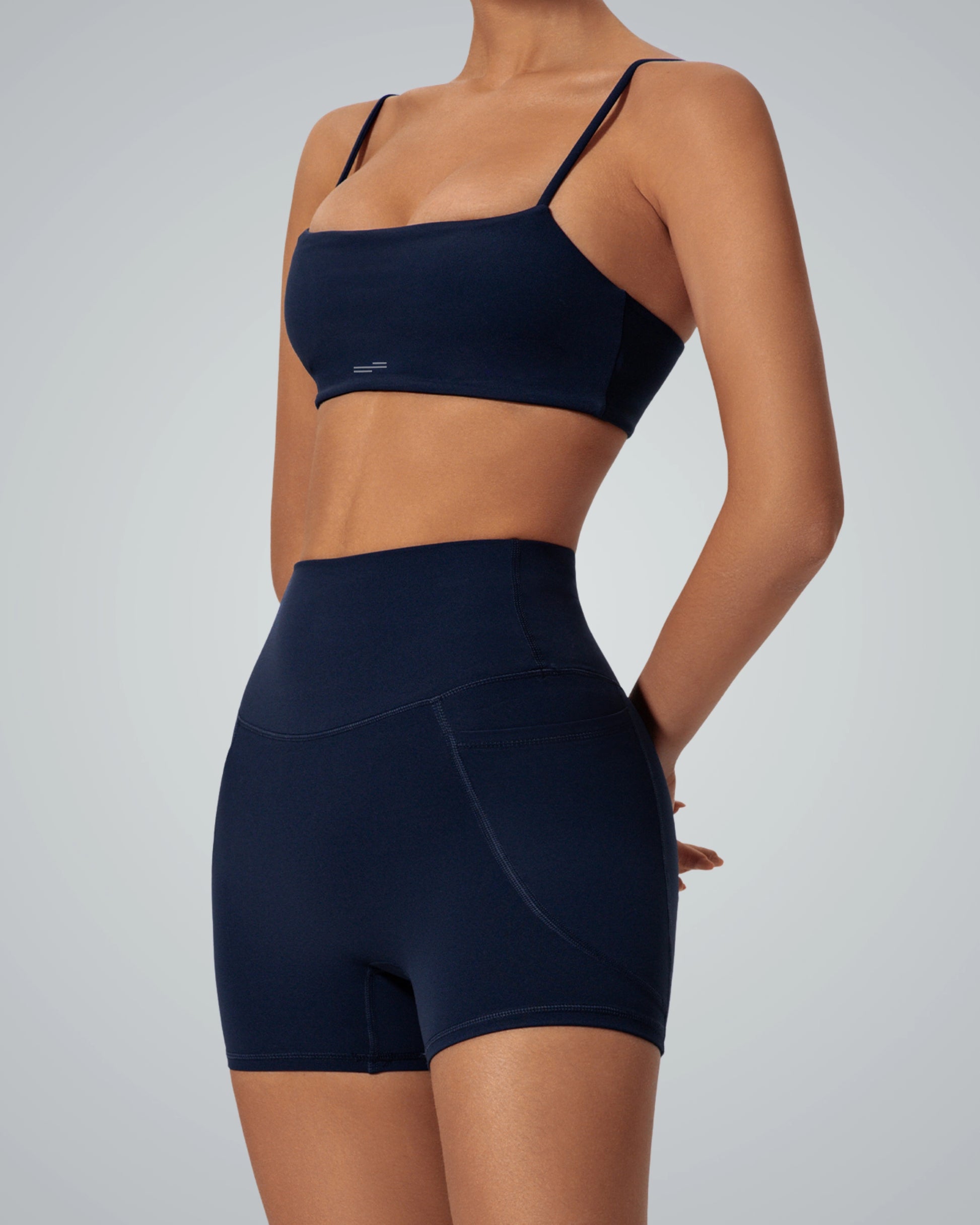 Woman modeling Bandsam FluidForce matching workout set with sports bra and high-waisted shorts, perfect for yoga and gym sessions.