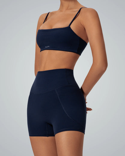 Woman modeling Bandsam FluidForce matching workout set with sports bra and high-waisted shorts, perfect for yoga and gym sessions.