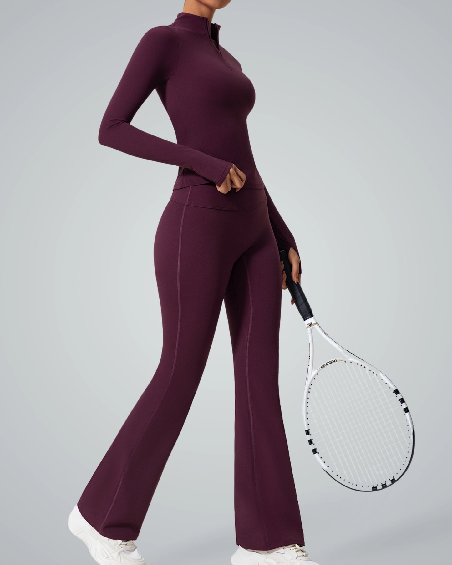 Woman in purple high-neck zip-up sportswear holding tennis racket, showcasing Bandsam's seamless gym set for performance and style.
