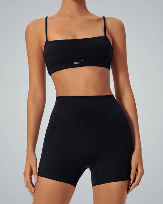 Woman wearing Bandsam GlowLift Bra in black, showcasing stretch, comfort, and support for yoga, pilates, or activewear lounging.