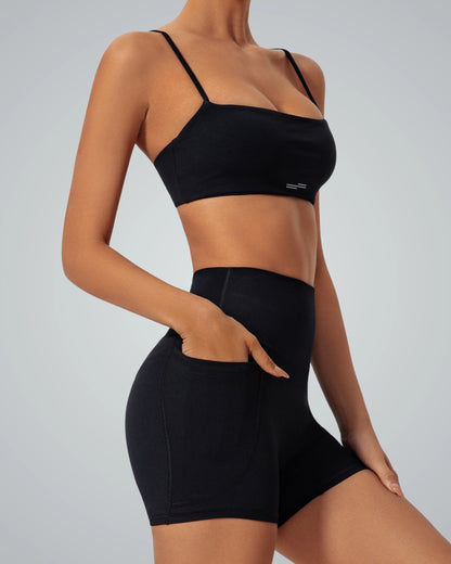 Woman wearing Bandsam GlowLift Bra and shorts, showcasing comfort, support, and flexibility for yoga, pilates, or lounging activities.