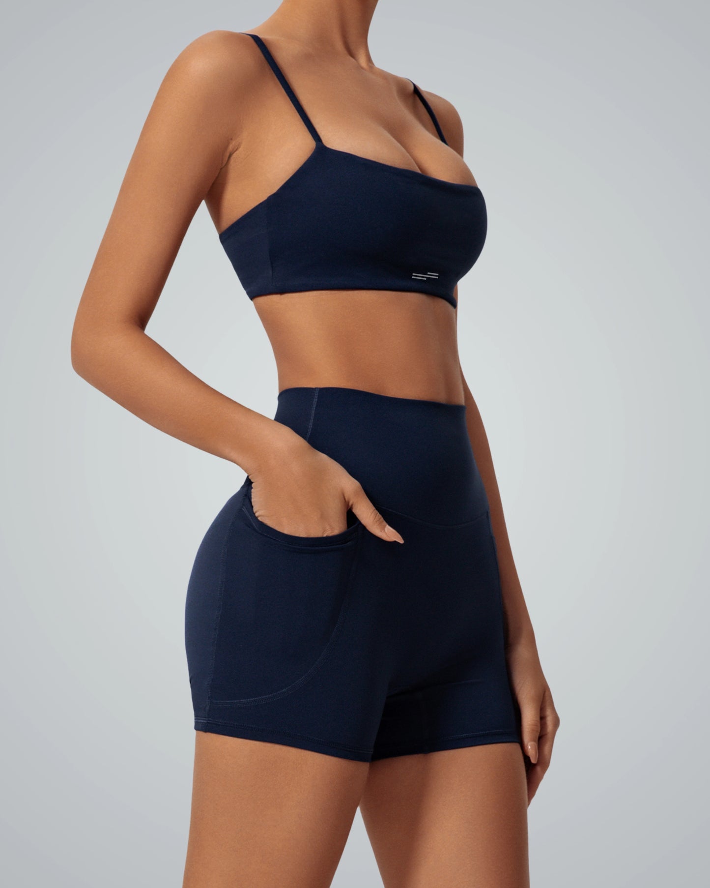 Woman wearing Bandsam GlowLift Bra and shorts, emphasizing stretch and comfort for yoga, pilates, and lounging.