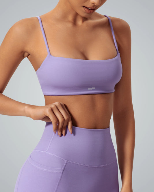 Woman wearing a purple Bandsam GlowLift Bra showcasing support, comfort, and flexibility ideal for yoga, pilates, and lounging.
