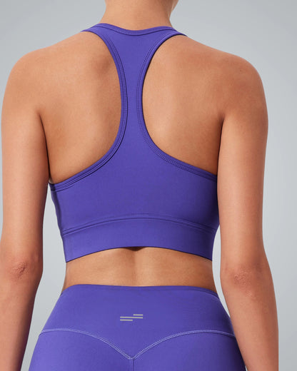 A woman is shown from the back wearing a Bandsam purple GlowMotion Bra and matching high-waisted leggings, standing against a light gray background.