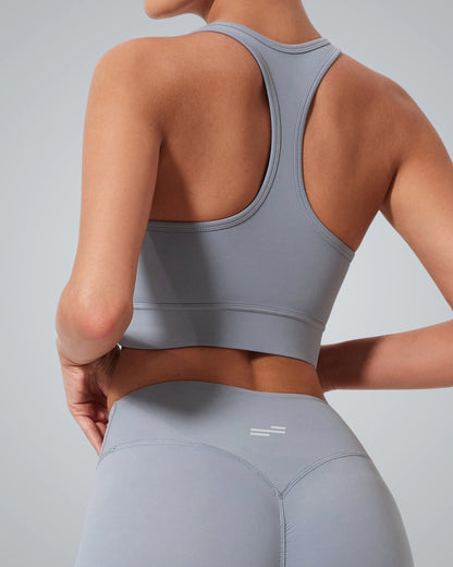 A woman is shown from the back wearing a Bandsam matching light gray high impact sports bra and leggings, standing against a plain gray background for optimal support.