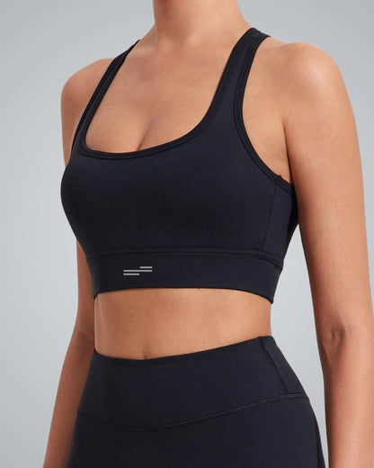 A woman wearing a supportive Bandsam sports bra and matching high-waisted leggings, shown from the side with her head cropped out, standing against a light gray background.