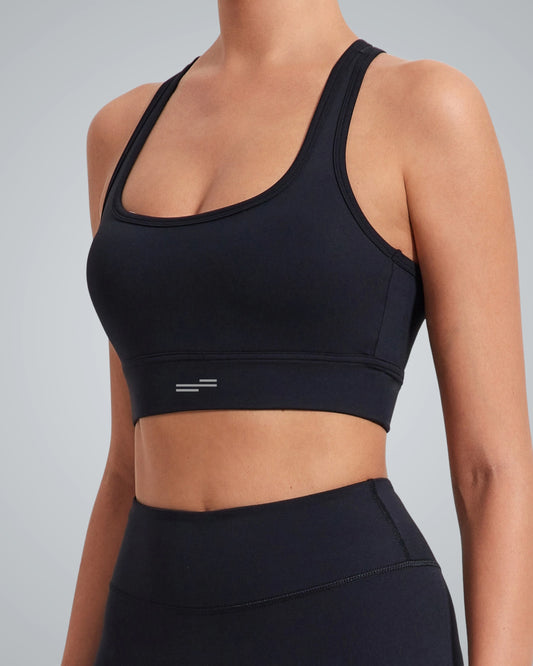 A woman wearing a supportive Bandsam sports bra and matching high-waisted leggings, shown from the side with her head cropped out, standing against a light gray background.