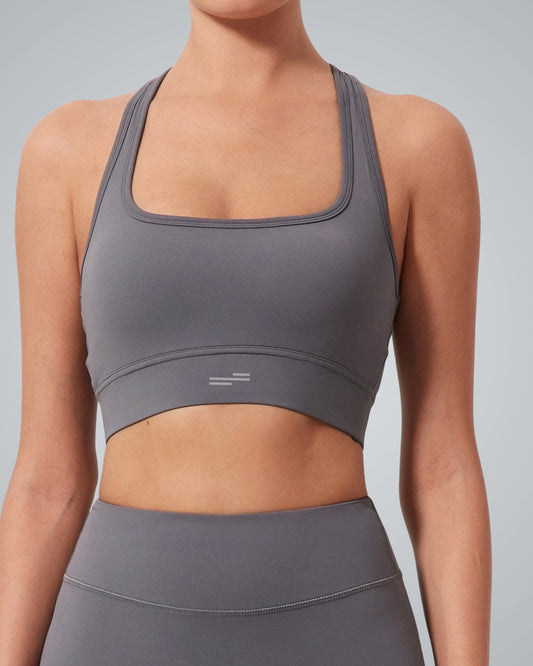 A woman wearing a gray high impact sports bra and matching high-waisted leggings from Bandsam, shown from the shoulders to hips, stands against a light gray background—ideal support for any active routine.