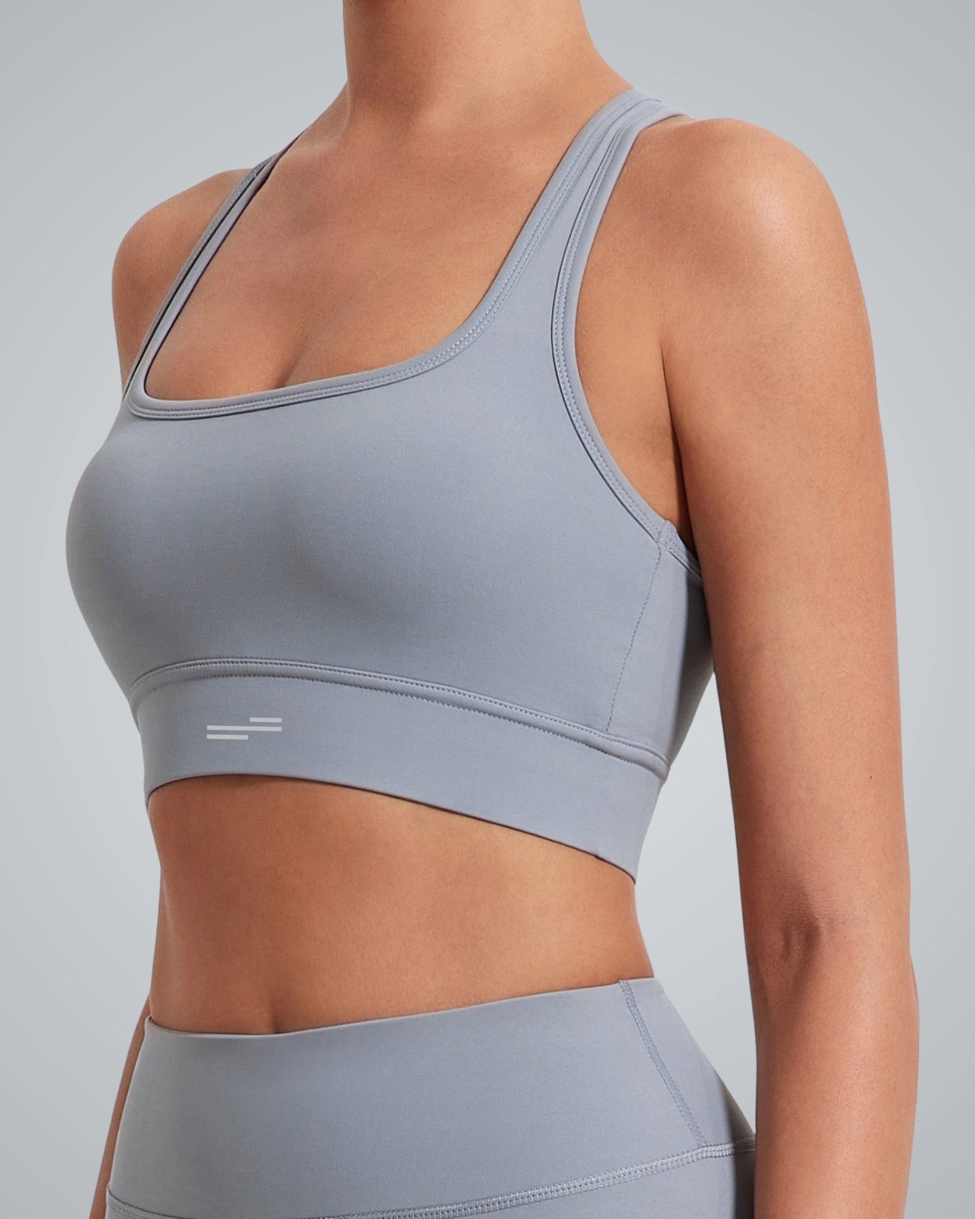 A woman wearing a Bandsam light gray high impact sports bra and matching high-waisted leggings, shown from the neck down against a plain gray background.