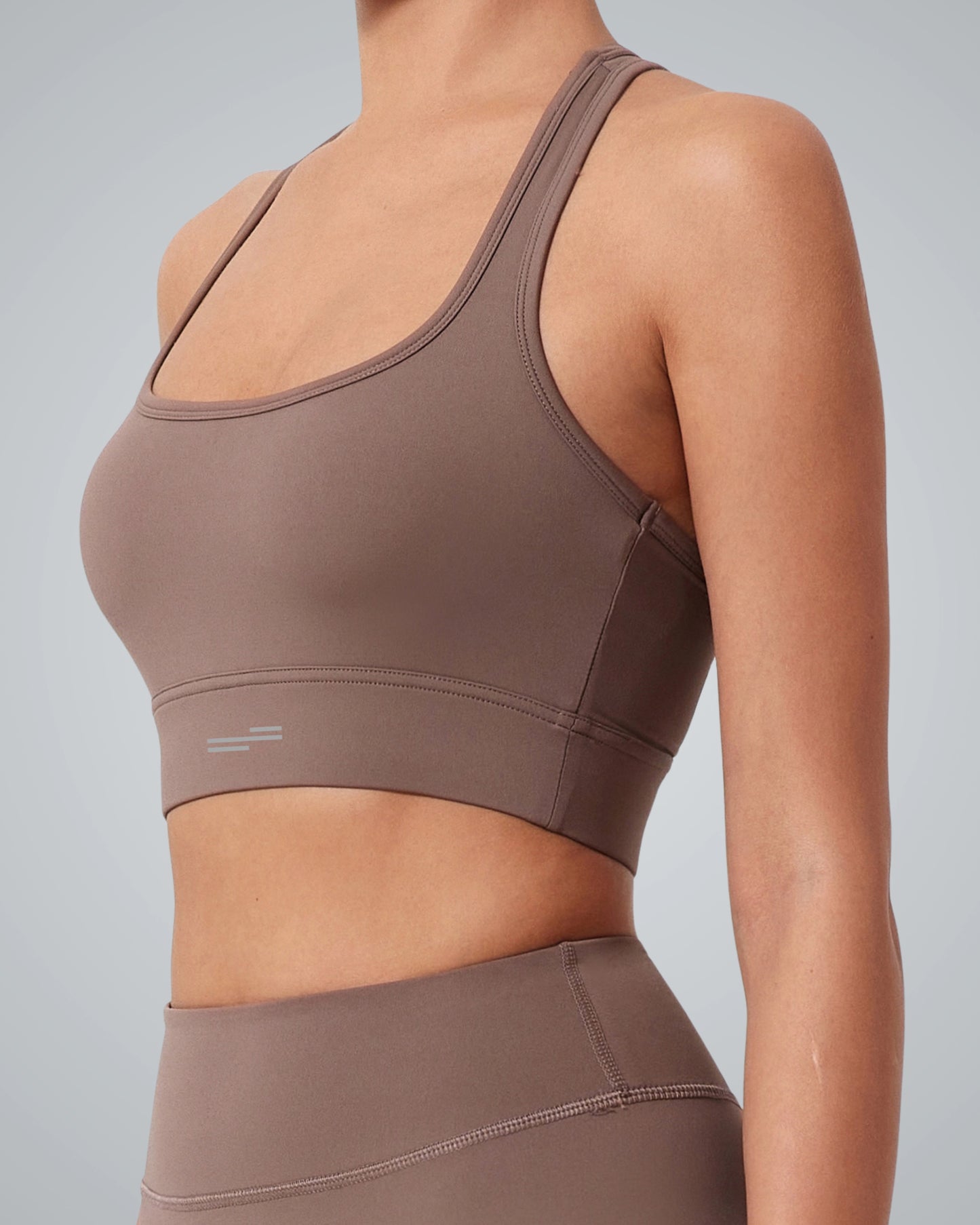 A person wearing a Bandsam GlowMotion Bra and matching high-waisted leggings stands against a plain light gray background. The sportswear is form-fitting with minimal seams and no visible logos.