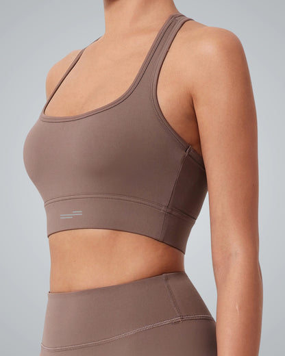 A person wearing a Bandsam GlowMotion Bra and matching high-waisted leggings stands against a plain light gray background. The sportswear is form-fitting with minimal seams and no visible logos.