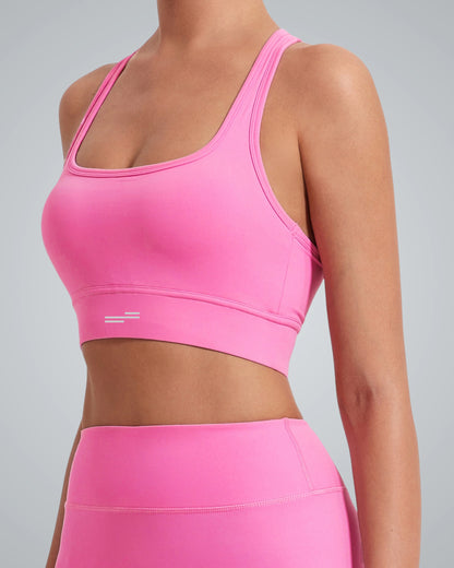 A women wearing a Bandsam bright pink GlowMotion Bra and matching high-waisted leggings, shown from the shoulders to the hips against a plain light gray background.