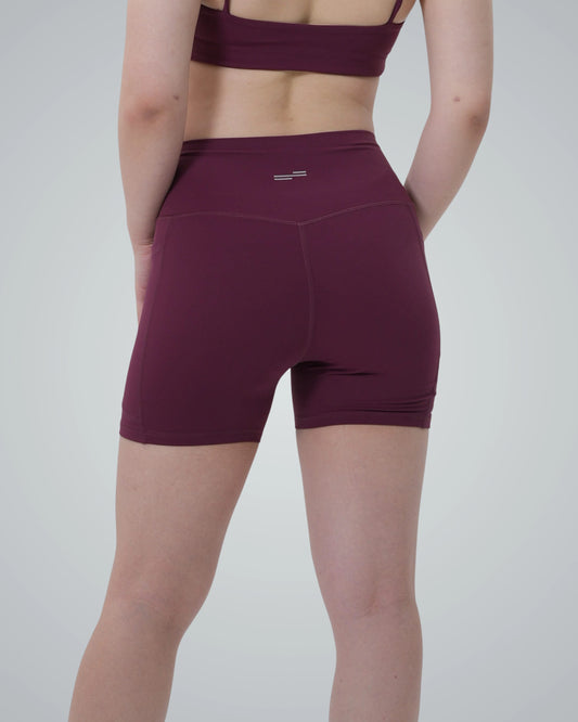 Woman wearing Bandsam LilaFit high-rise shorts in burgundy, showcasing stretch and comfort for yoga, workout, or lounging.