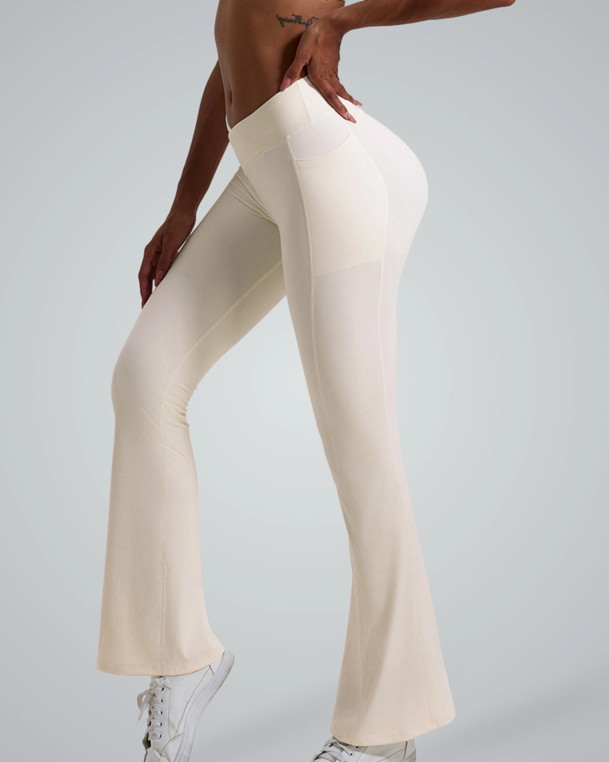 Woman wearing cream-colored Bandsam PeakFit Pocket Leggings, high-waisted and flared, ideal for yoga, pilates, or casual outings.