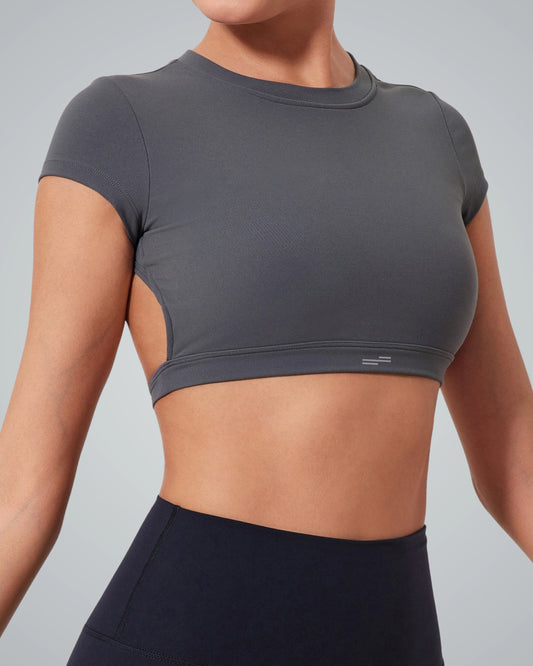 A woman wearing a Bandsam fitted short-sleeve ScarletFlow Top with an open back and high-waisted black leggings, shown from the shoulders to the hips against a plain light background—perfect for updating your exercise wardrobe.