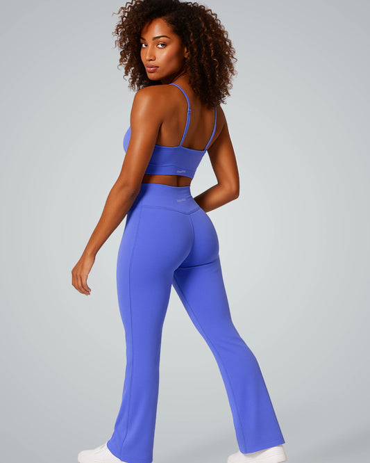 Woman modeling Bandsam SculptEase stylish activewear set with twist-front sports bra and high-waisted V-shaped flared trousers in blue.