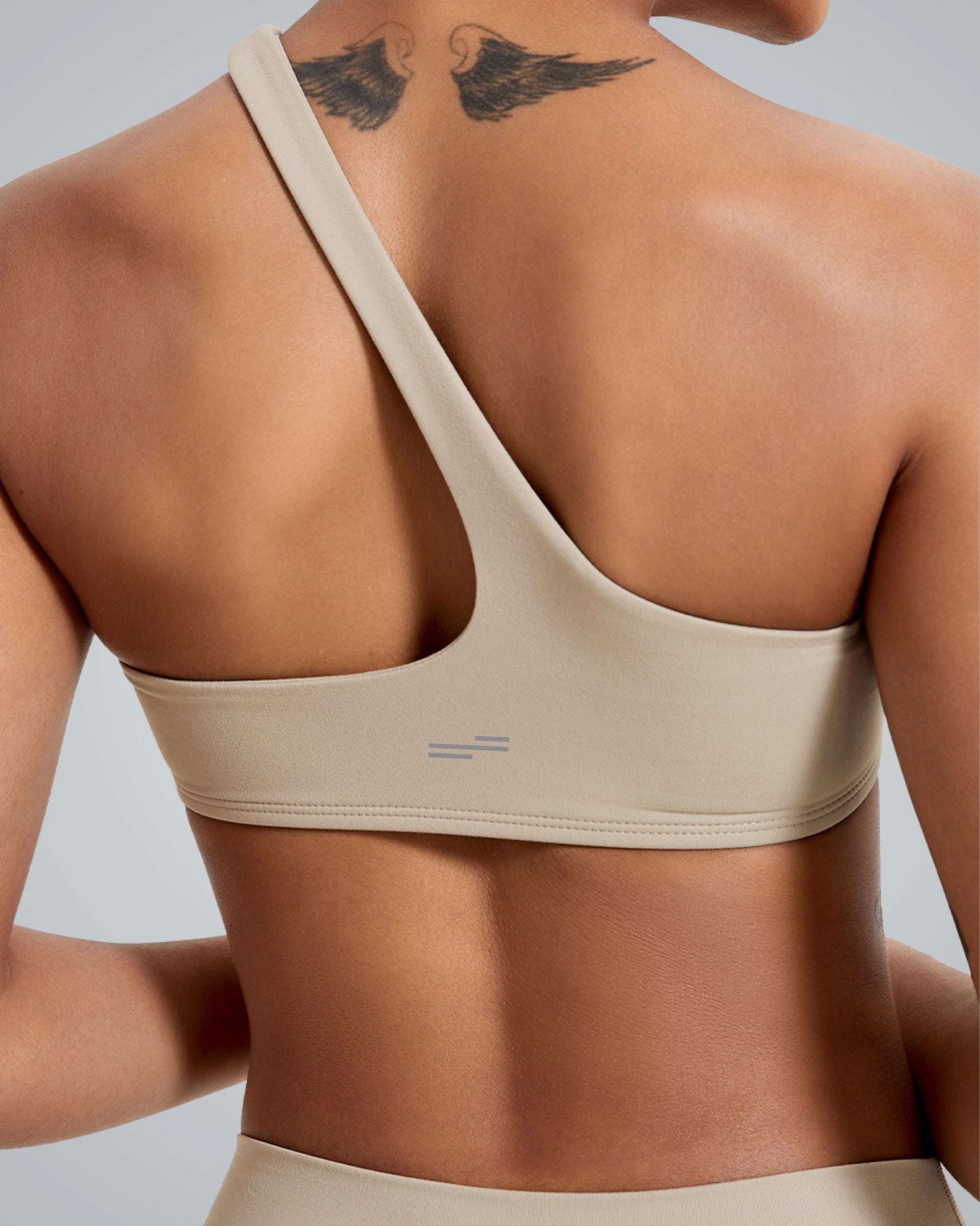 Close-up of a beige asymmetrical sports bra from the ToneTwin Set by Bandsam. Perfect for yoga and workouts. Stylish and supportive.
