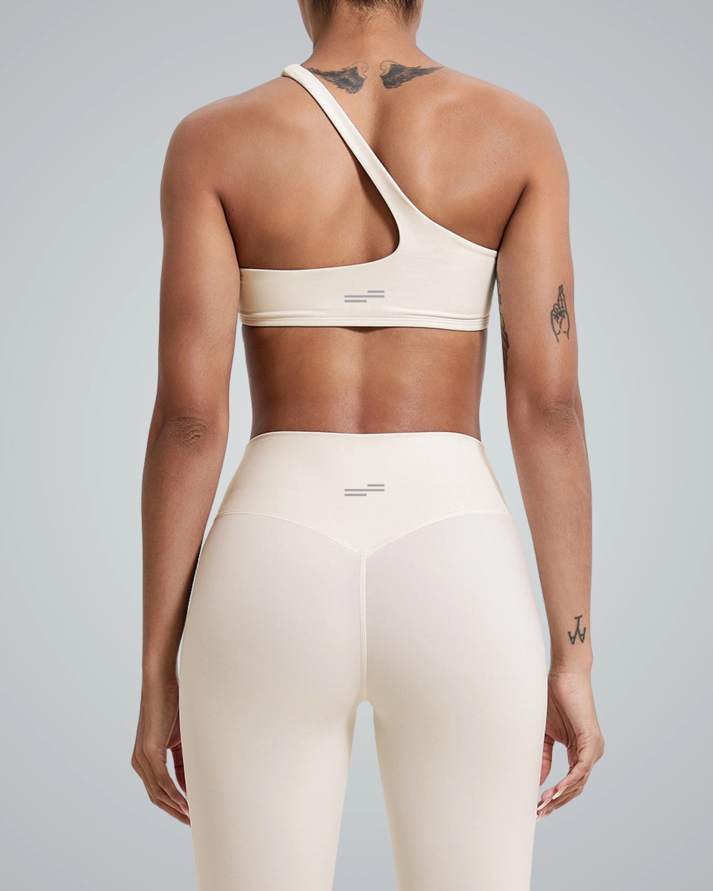 Back view of Bandsam's ToneTwin Set featuring an asymmetrical top and high-waisted leggings, a matching workout set in minimalist style.