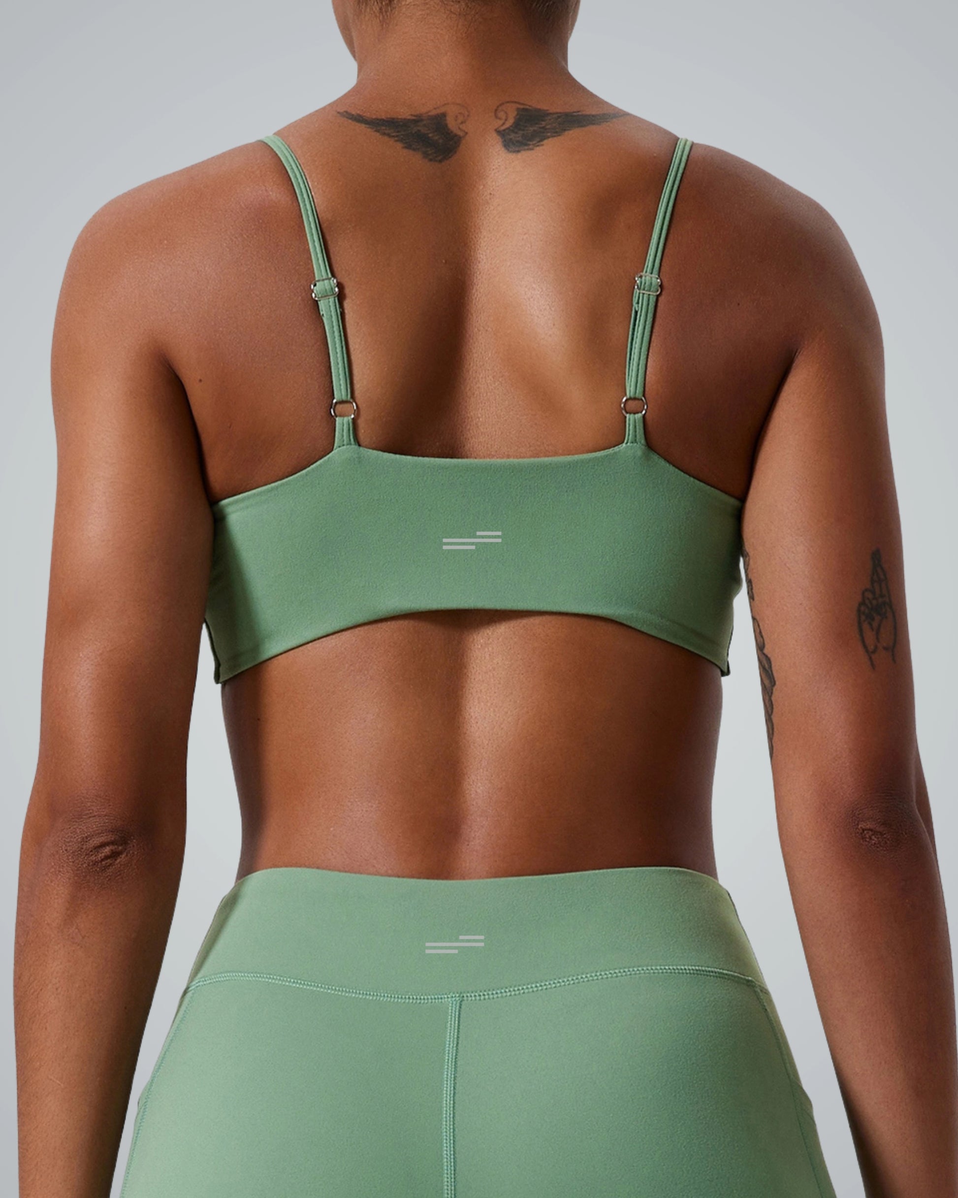 Back view of woman wearing Bandsam TwistFit Bra in green, highlighting stretch, soft activewear for yoga and workouts.