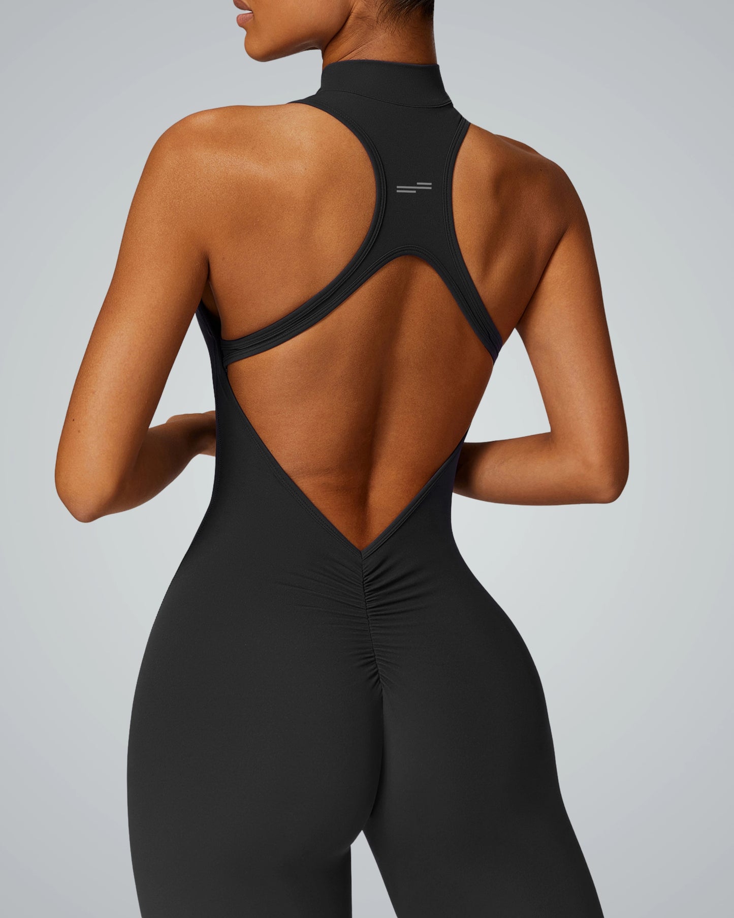 Woman wearing Bandsam VelocityVibe Jumpsuit, showcasing high-neck, open back design. Perfect for stretch, workout, yoga, pilates.